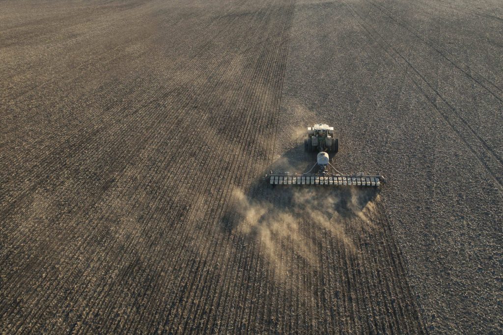Aerial view of a tractor with seed disc openers working on a freshly tilled field